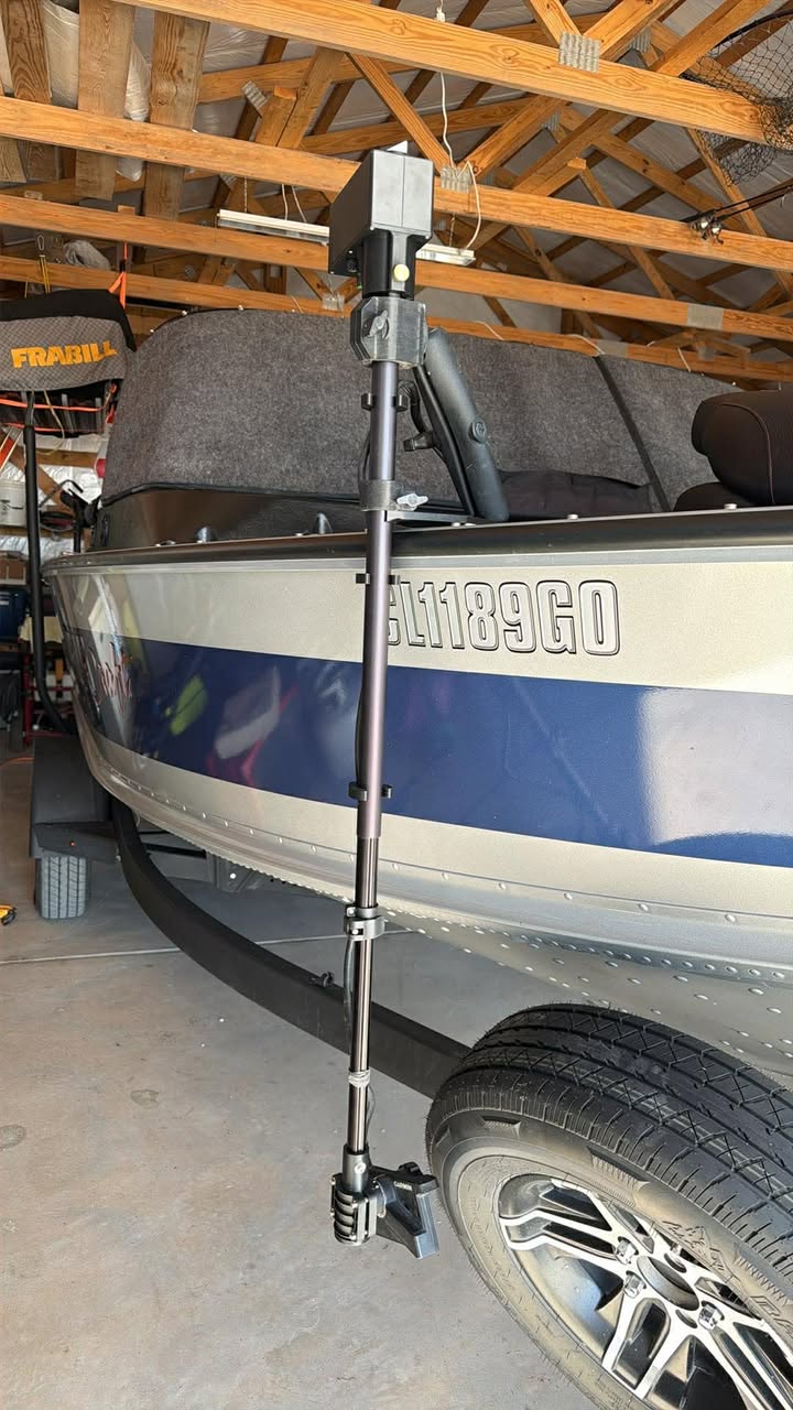A close-up of a blue and silver boat above a black tire, featuring a shallow water anchor system and the Wireless Transducer Pole - First Mate XT mounted near the GL1189GO registration number in a garage.
