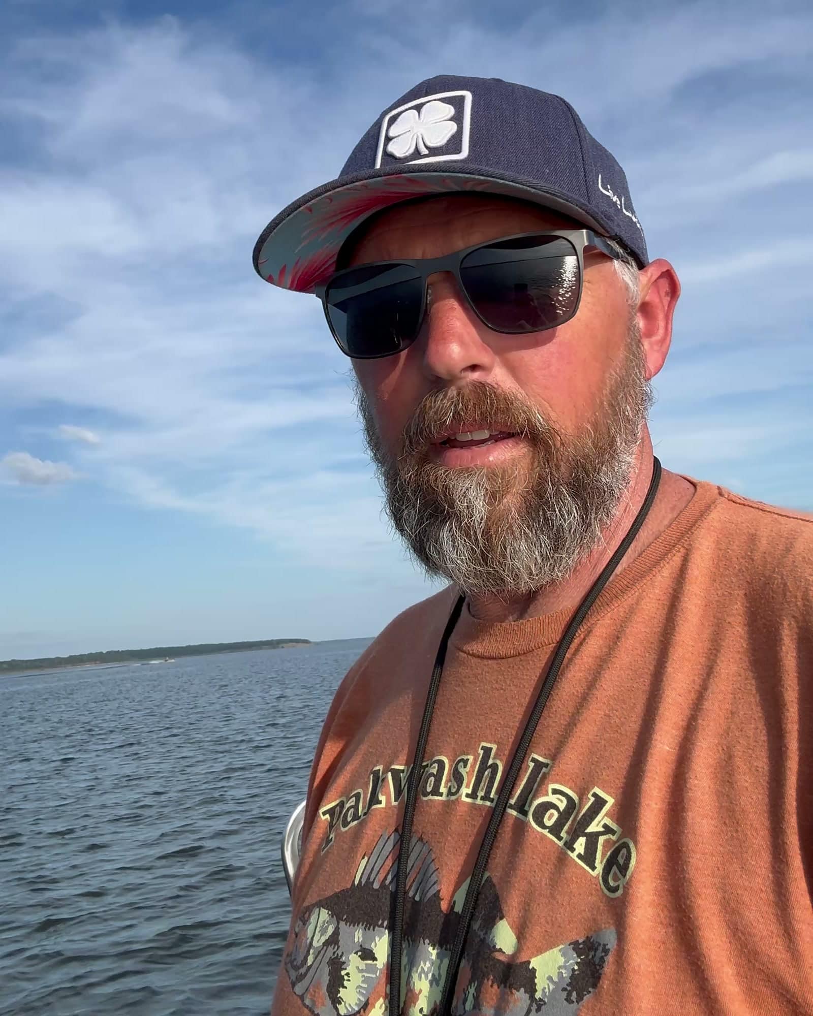 Founder of First Mate Fishing on the water, chest up, lake and shoreline behind him