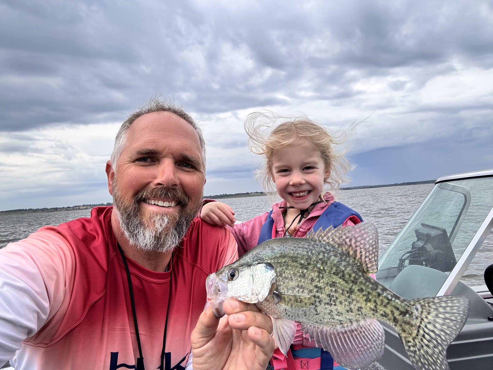 First Mate Fishing founder and his granddaughter holding a crappie on the bow of the boat